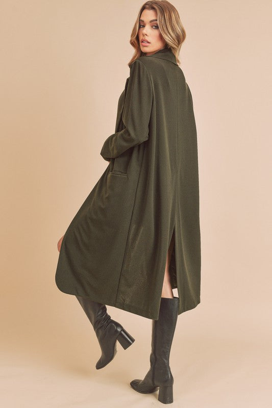 Woman wearing a long olive green coat on a beige background